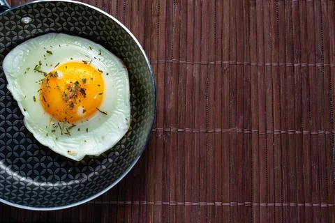 Frying pan with fried egg on a bamboo table Stock Photos