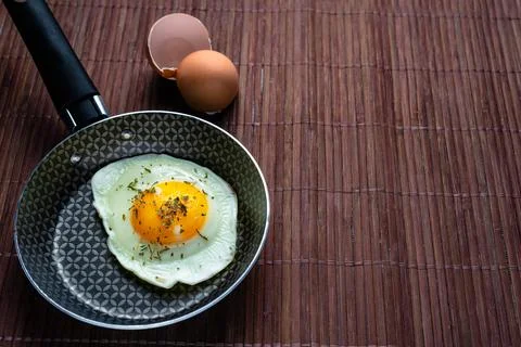 Frying pan with fried egg on a bamboo table Stock Photos