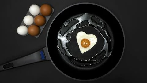 A frying pan with a fried egg in the shape of a heart Stock Photos