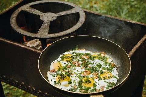 Frying pan of fried eggs, bacon and organic greens, green grass on the Stock-Fotos