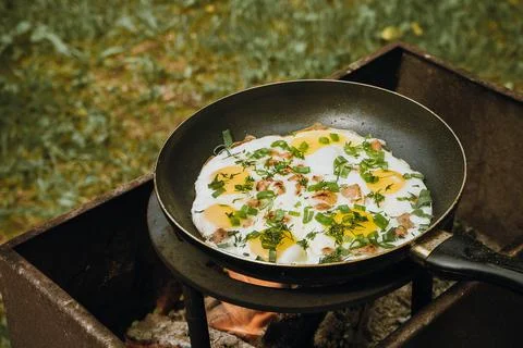 Frying pan of fried eggs, bacon and organic greens, green grass on the Stock-Fotos