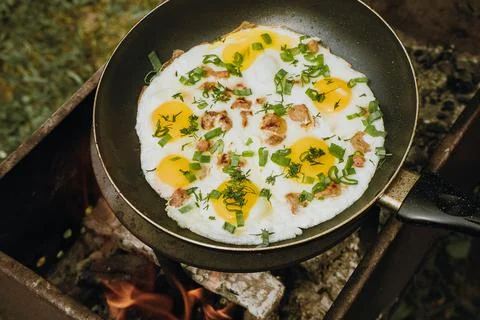 Frying pan of fried eggs, bacon and organic greens, green grass on the Stock Photos