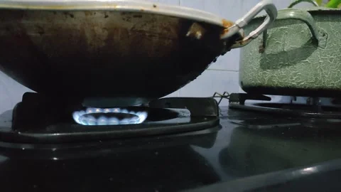 A frying pan on a gas stove with a bright blue flame glowing underneath Stock Footage 295173217