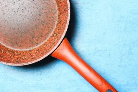 Frying pan with granite coating on blue background. Copy space. Top view. Dis Stock Photos