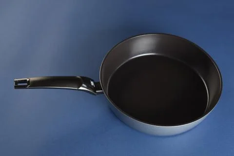 Frying pan with handle on blue background. Top view Photos