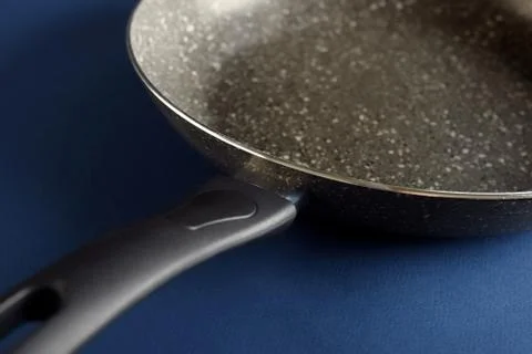 Frying pan with handle on blue blurred  background. Macro view Stock-Fotos