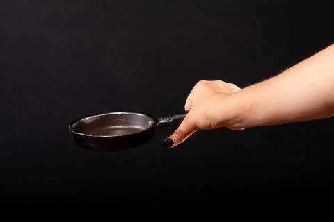 Frying pan held by woman's hand. isolated black background Stock Photos