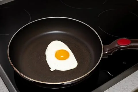 Frying pan on the hob with fried eggs from one egg with yolk Stock Photos