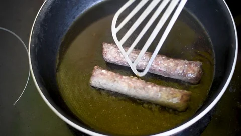 Frying pan on a hot plate with vegetable oil and   fried sausages Stock Footage 95066710
