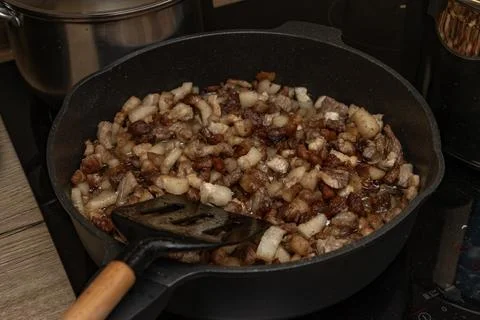Frying pan on an induction hob, mixing sliced ??beef, pork, and bacon in a .. Stock Photos