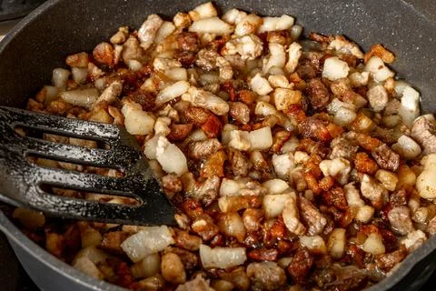 Frying pan on an induction hob, mixing sliced ??beef, pork, and bacon in a .. Stock Photos
