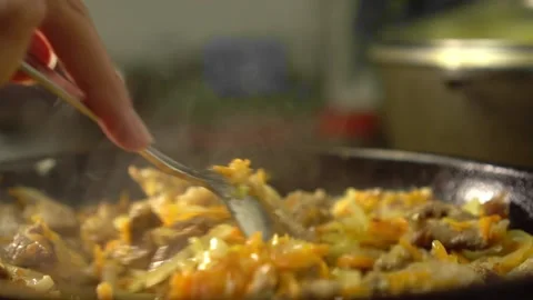 Frying pan with meat and vegetables close-up. Female rka mixes contents. Stock Footage 191630673