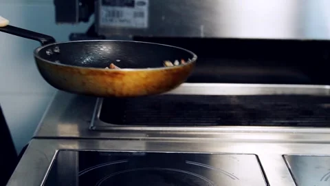 Frying pan with meat on a hot stove. Professional cook turning over pieces Stock Footage 318310381