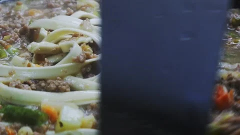 In a frying pan with minced meat and vegetables, stir the udon with a spoon.. Vidéo 299396817