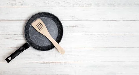 Frying pan with non-stick ceramic coating and spatula on a white wooden backg Stock Photos