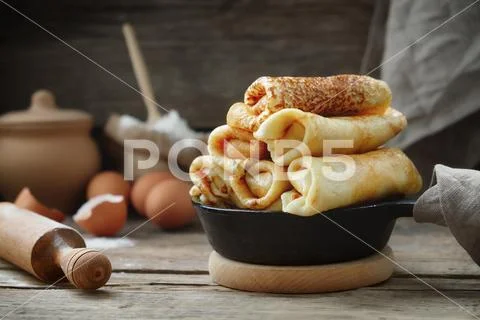 Frying pan of pancakes, ingredients and kitchenware for pancakes making. Stock Photos