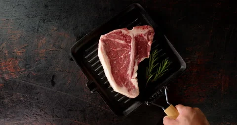 A frying pan with raw beef t-bone steak is put on table. Stock Footage 139537410