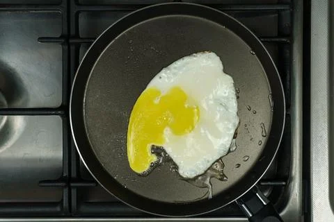 A frying pan with scrambled eggs is on the stove. Close-up Stock Photos