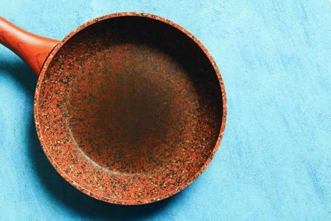 Frying pan with a stone coating on a blue background. Copy space. Top view. D Stock Photos