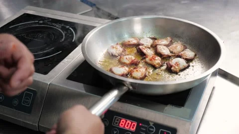 Frying pan on the stove.chef throws pieces of octopus for cooking in restaurant Stock Footage 163971181