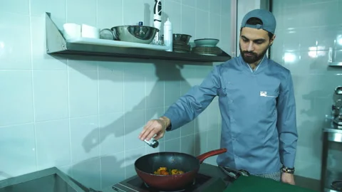 Frying pan with vegetables in chef hand. Male chef cooking vegetables at Stock Footage 87429539