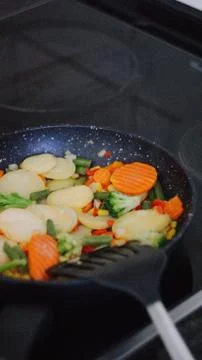 Frying pan with vegetables on an electric stove / clouse up Stock Photos