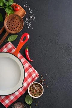 Frying pan white , black empty plate, basil leaves and spices on dark stone b Stock Photos