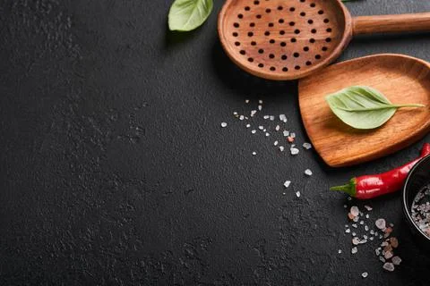 Frying pan white , black empty plate, basil leaves and spices on dark stone b Stock Photos