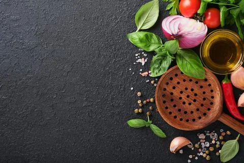 Frying pan white , black empty plate, basil leaves and spices on dark stone b Stock Photos