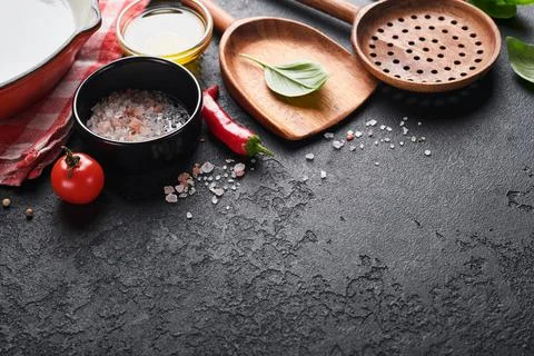 Frying pan white , black empty plate, basil leaves and spices on dark stone b Stock Photos