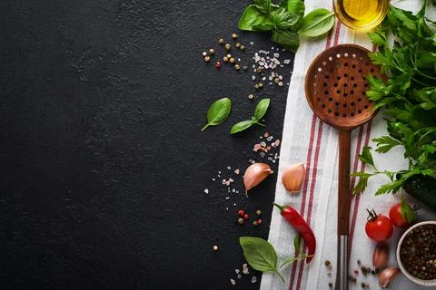 Frying pan white , black empty plate, basil leaves and spices on dark stone b Stock Photos