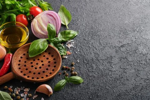 Frying pan white , black empty plate, basil leaves and spices on dark stone b Stock Photos