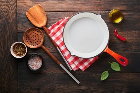 Frying pan white, black empty plate, basil leaves and spices on old wooden ba Stock Photos
