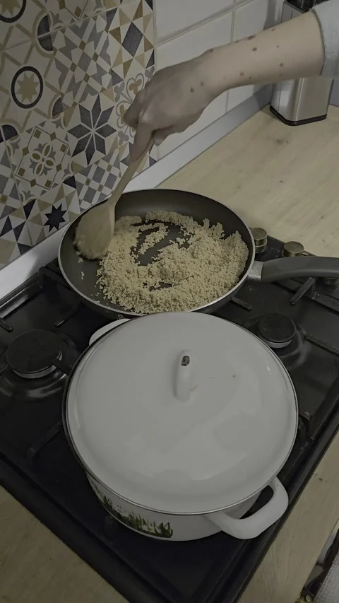 Frying in a pan with a wooden spoon in a kitchen 库存影片 327985195