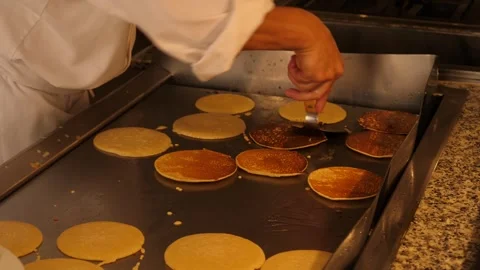 Frying pancakes on a large metal surface in the kitchen of a hotel restaurant Stock Footage 294322298