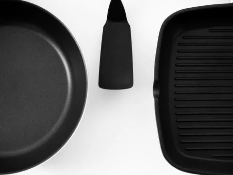 Frying pans hanging on a white wall Stock Photos