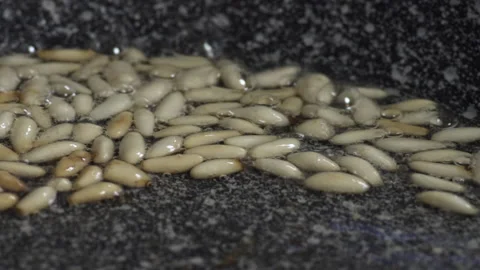 Frying pine nuts in hot oil using a frying pan, close up Stock Footage 134967268