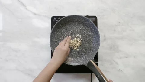 Frying pine nuts in hot oil using a frying pan Stock Footage 134967629