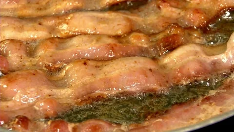Frying pork bacon in a pan, macro view close up. Sizzling tasty bacon strips. 스톡 동영상 334643279