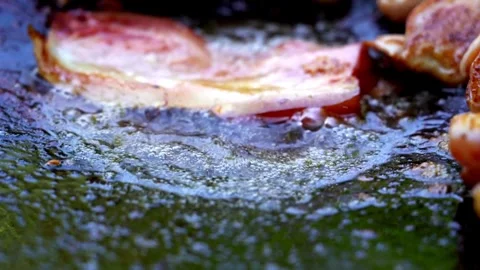 Frying pork bacon in a pan, macro view close up. Sizzling tasty bacon strips. 스톡 동영상 334643348