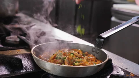 Frying pork meat strips in a pan, adding herbs - close up Stock Footage 175275802