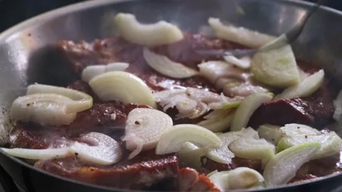 Frying pork neck steaks and onions in skillet, slow zoom out Stock Footage 336094024