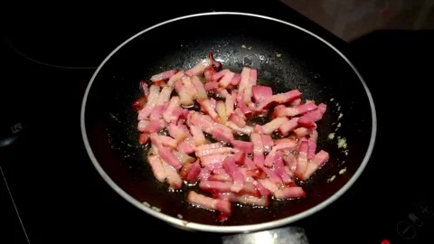 Frying pork tiny bacon dices, closeup. Classic, smoky and crispy bacon. 스톡 동영상 334643462