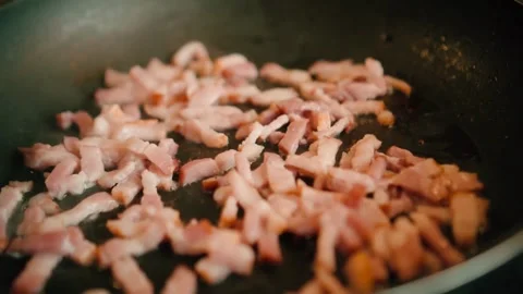 Frying pork tiny bacon dices, closeup. Classic, smoky and crispy bacon. 스톡 동영상 334643495