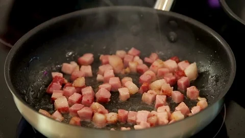 Frying pork tiny bacon dices, closeup. Classic, smoky and crispy bacon. 스톡 동영상 334643503