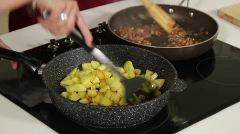 Frying potatoes and onions with bacon in two pans Stock Footage 49782009