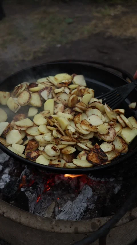 Frying Potatoes Over Open Campfire Flames for Delicious Outdoor Meal Stock Footage 337105823
