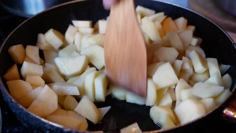 Frying potatoes in a pan and stirring with a wooden spatula Stock Footage 169012291