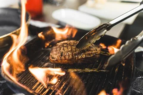 Frying process of striploin steak. Piece of medium rare piece of meat on grill Stock Photos