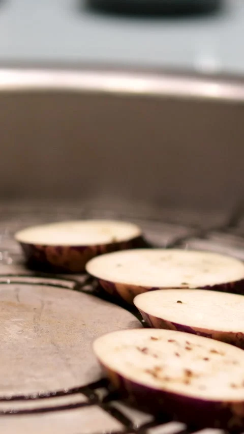 Frying of purple eggplants sliced along in cooking oil in grilling pan on stove Vídeo Stock 302801332